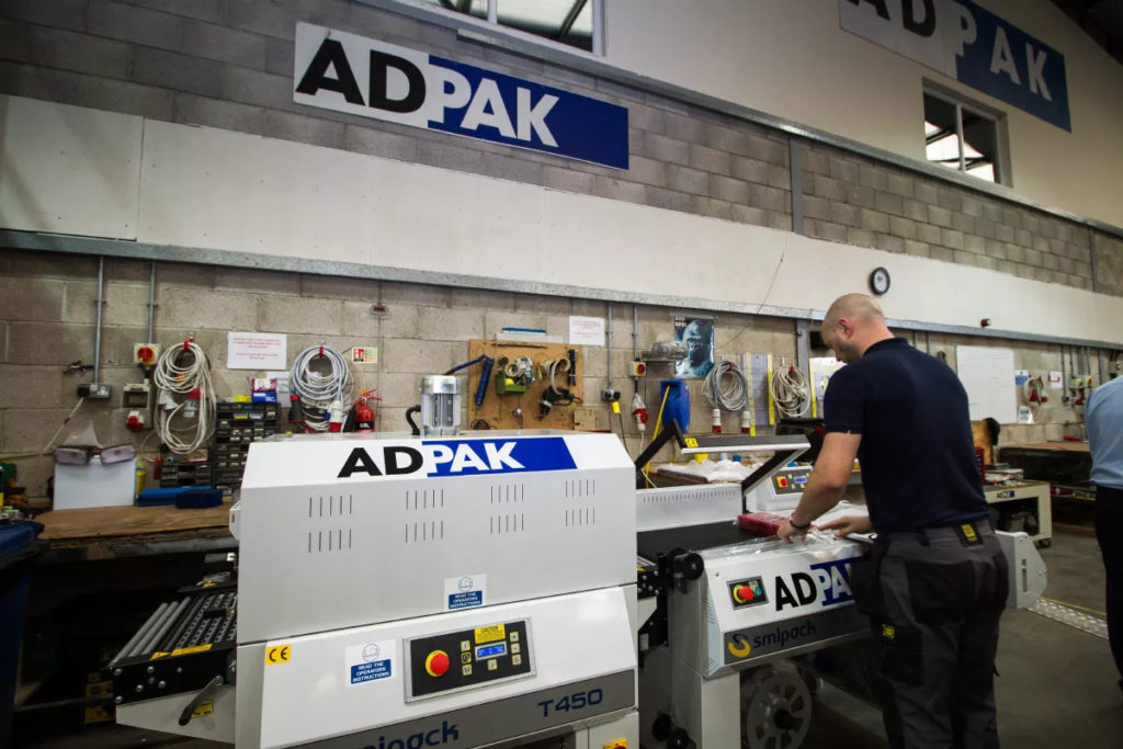 adpak worker using sealing machine